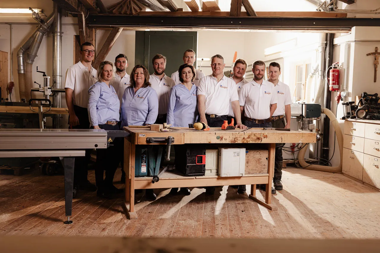 Gruppenfoto des Teams in der Werkstatt, Personen stehen hinter einer Werkbank